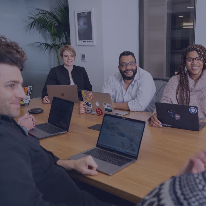 people with laptops around a table